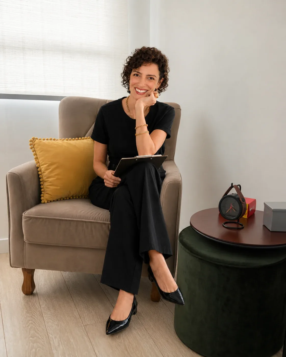 Juliana Pupo, psicóloga e hipnoterapeuta em Campinas, sorrindo sentada na poltrona do consultório